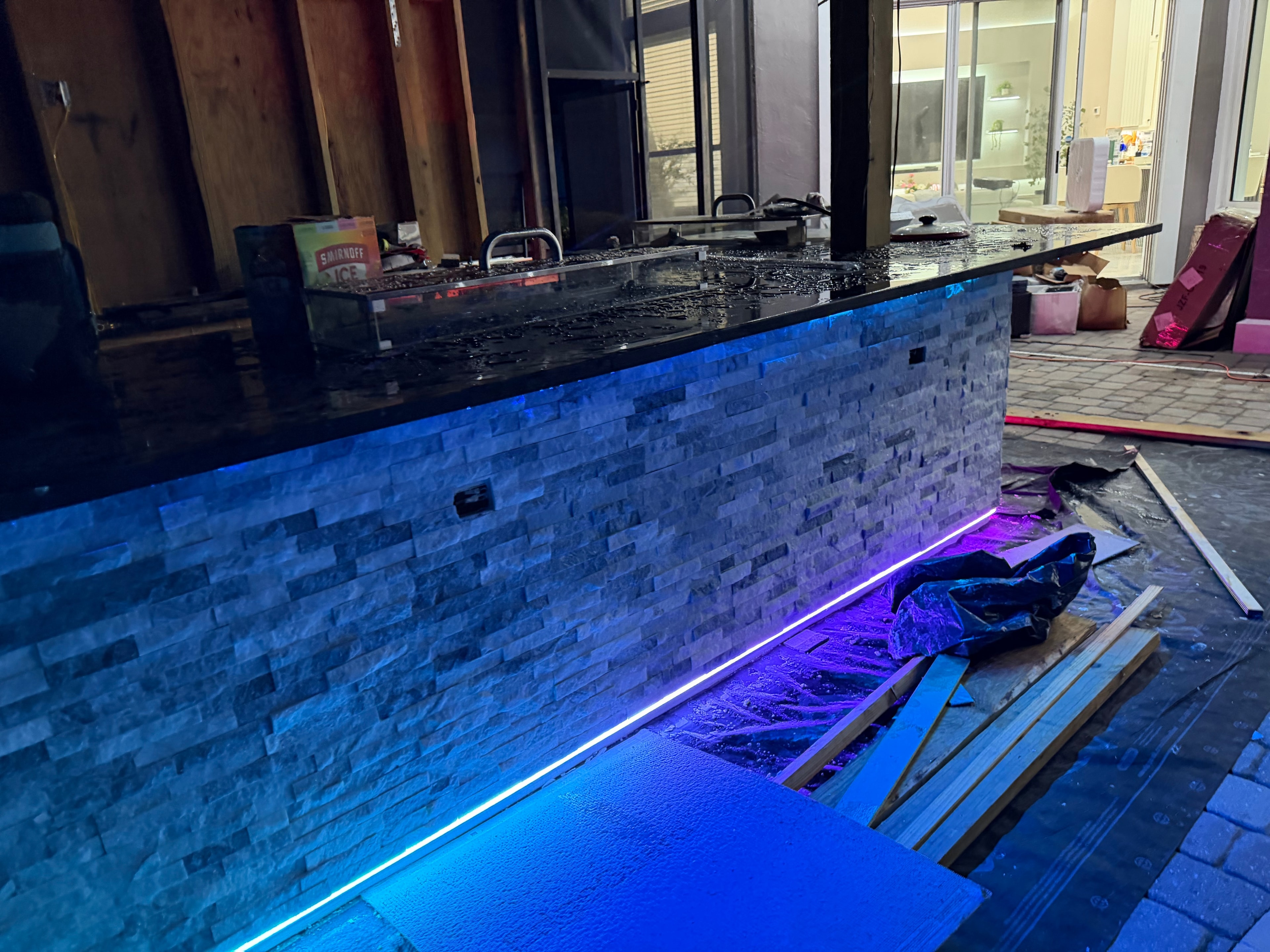 Custom bar with blue LED accent lighting under stone facade